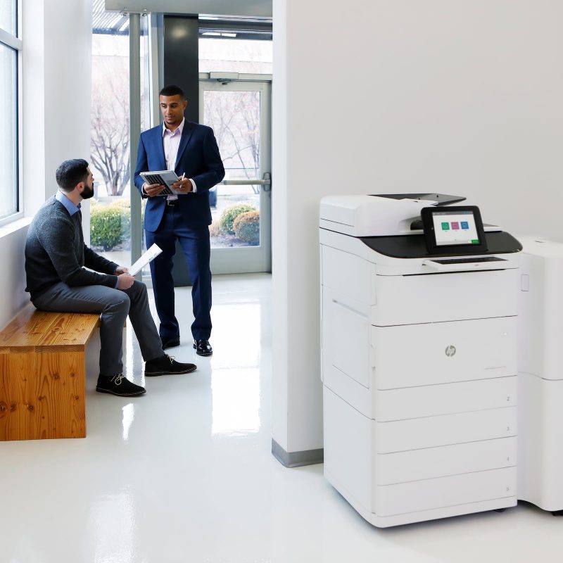 Two men in an office with an HP printer scanner
